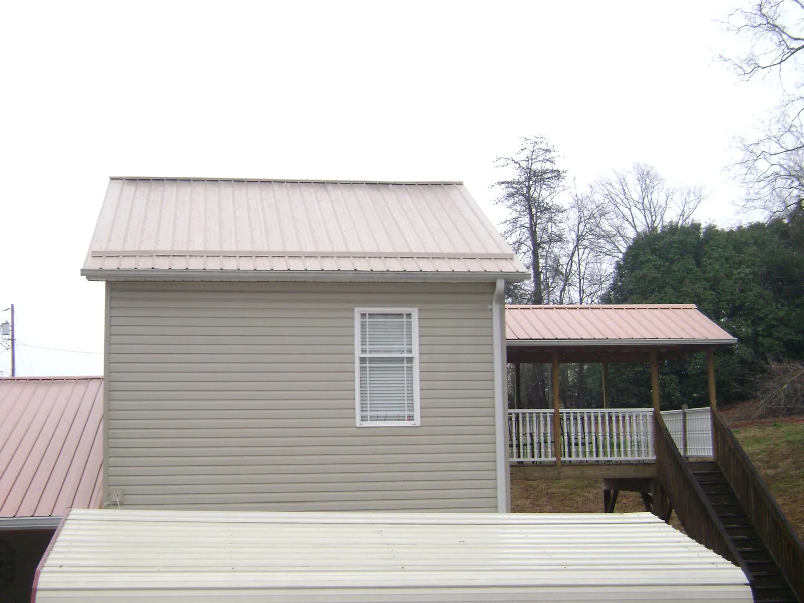 Tan metal roofs on a two story addition and attached porch, from a Roof Replacement job in Silverdale