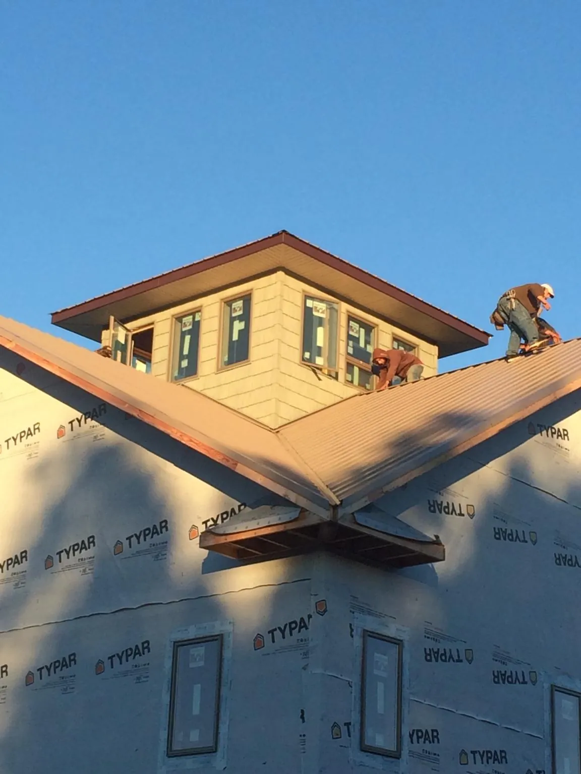 Roofers working around a rooftop cupola on a new metal roof at sunset — Roof Waterproofing in Silverdale by Roofing Brothers